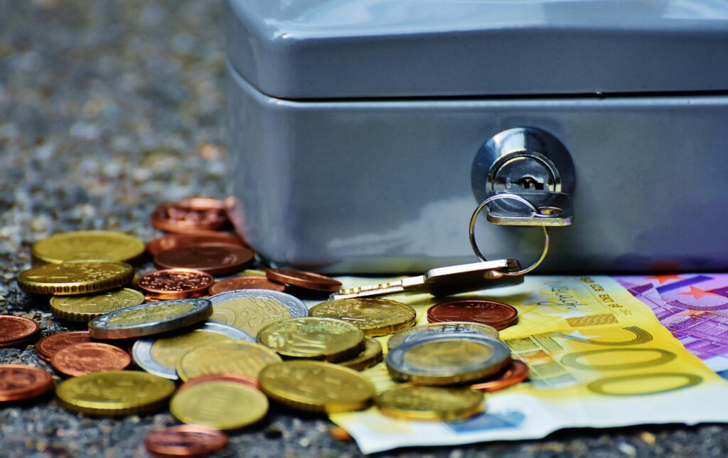 Banknotes and coins beside gray safety box